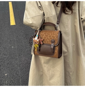 Detail of vintage crossbody bag with leopard print flap and cute bear keychain on model