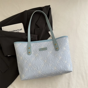 Floral embroidered light blue tote bag with elegant leather straps on minimalist background