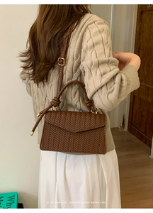 Brown woven leather shoulder bag showing V-pattern texture and knot handle detail