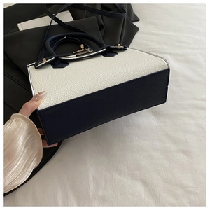 Dettaglio della borsa in pelle motivo litchi con contrasto bianco e nero e chiusura oro