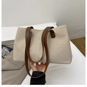 Dettaglio della borsa tote in tela con manici in pelle marrone e trama del tessuto