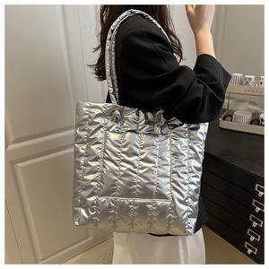 Detail of the silver quilted tote bag with metallic texture and wide padded shoulder strap