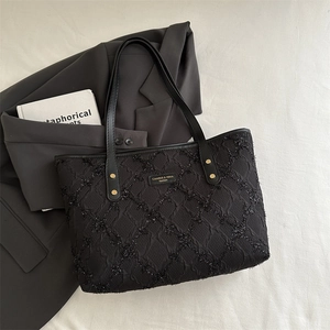 Minimalist black tote bag with textured shimmer fabric shown from a 45-degree angle view