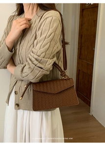 Detail of a brown woven leather crossbody bag with thin straps and gold hardware