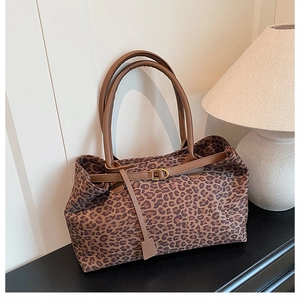 Detail of leopard print tote bag with brown buckle strap and gold metal hardware finish