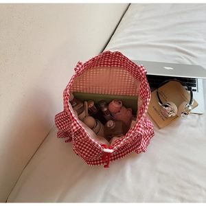 Top view of red gingham tote bag filled with a water bottle, umbrella, and tablet