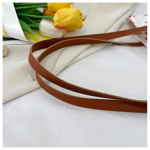 Detail of brown faux leather shoulder strap with fine stitching on a printed tote bag