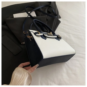 Dettaglio borsa tote bicolore con chiusura dorata e texture in pelle martellata