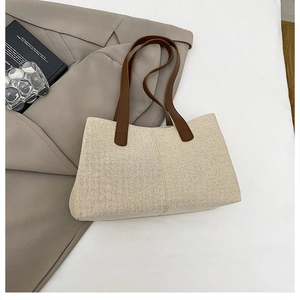 Vista dall'alto di borsa tote intrecciata beige con manici in pelle marrone su blazer