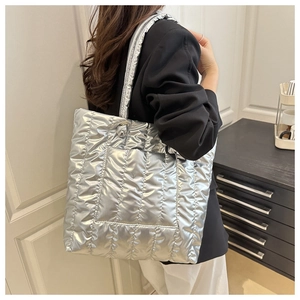 Metallic silver quilted tote bag styled with black blazer in a minimalist indoor setting