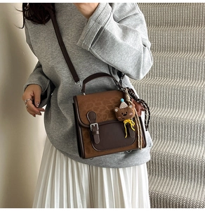 Close-up of retro color-block crossbody bag with bear plush charm and silk scarf detail