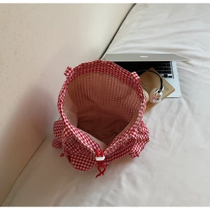 Detail of red and white gingham tote bag with adjustable drawstring closure and brown lining