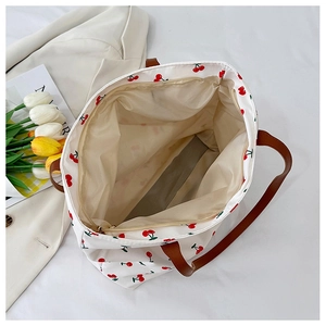 Detail view of large cherry print tote bag with brown faux leather handles and zipper