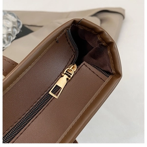 Close-up of golden zipper and textured brown leather surface on a commuter tote bag