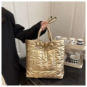 Detail of metallic gold quilted puffer tote bag with handles and crossbody strap