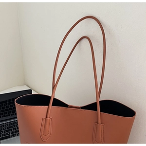 Dettaglio della borsa tote in pelle caramello con spalline sottili e cuciture rifinite