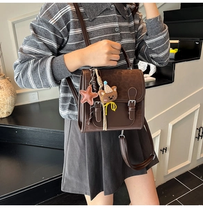 Brown retro crossbody bag with bear charm and double buckle flap in a college style