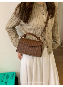 Detail of the woven texture and top handle on this dark brown crossbody bag for women