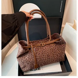 Detail of leopard print tote bag featuring brown leather handles and metal buckle accents