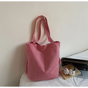 Detail of red and white checkered canvas tote bag with side pocket in a minimalist setting