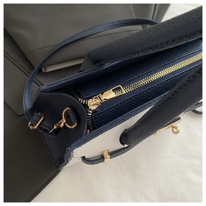Dettaglio della borsa in pelle martellata con cerniera dorata e design bicolore chic