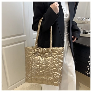 Détail d'un sac cabas matelassé doré brillant avec texture bouffante et poche externe