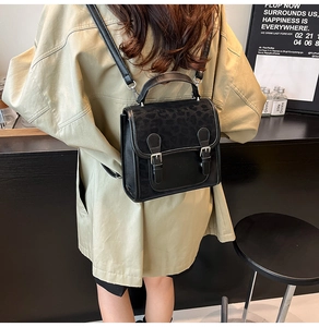 Detail of black mini backpack with leopard texture flap and metallic buckle accents
