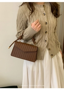 Close-up of brown woven texture handbag with knotted handle and minimalist retro vibe