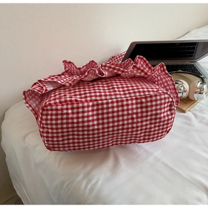 Detail of red and white checkered canvas tote bag with ruffled edges on white background