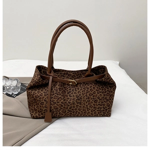 Detail of leopard print tote bag with brown straps and golden metal buckle accents
