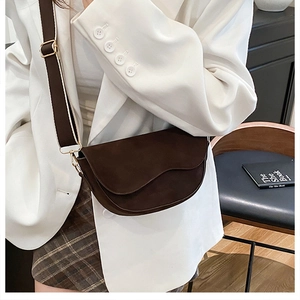 Détail du sac besace marron foncé avec rabat ondulé et large bandoulière en tissu