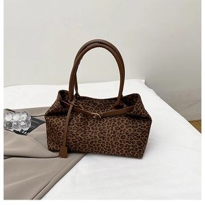 Detail view of the leopard print tote bag with brown leather handles and golden buckles