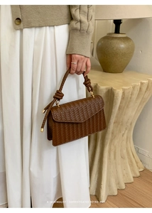 Detail of dark brown woven handbag with retro textured pattern and knot handle style
