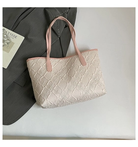 Flat lay of off-white quilted tote bag with pink straps next to a fashion art book