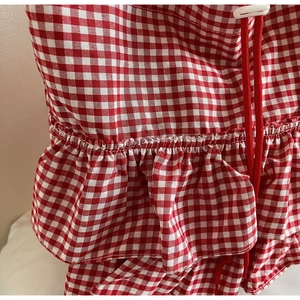 Detail of red gingham pattern with tiered ruffles and adjustable drawstring cord