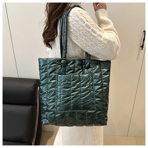 Model showing dark green metallic quilted tote bag with vertical stitching and front pocket