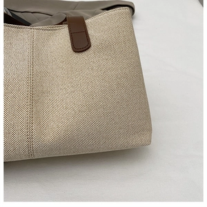 Dettaglio della borsa tote in tela beige con finiture dei manici in pelle marrone