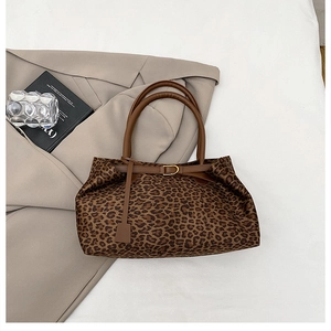 Macro detail of leopard print tote bag featuring brown leather handles and metal hardware