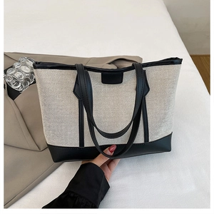 Detailed macro view of the canvas material and black leather handle on the tote bag