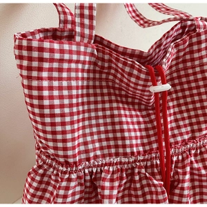 Detail of red and white gingham canvas tote bag showing drawstring closure and fabric texture