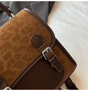 Detailed close-up of vintage brown color-block handbag with metallic buckle and fine stitching