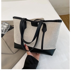 Detail of minimalist cream canvas tote with black leather trim and dual handles