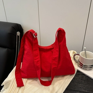 Sac hobo rouge en nylon léger avec large bandoulière réglable dans un décor lifestyle