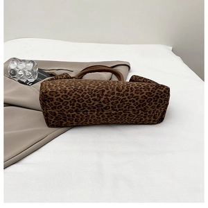 Close-up of leopard print tote bag with brown leather handles on minimalist background