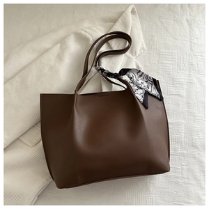 Detail view of large dark brown tote bag with stylish silk scarf on the handle