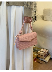 Detailed view of pink woven texture flap bag with knotted handle and gold metal accents