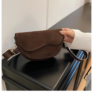 Detail of dark brown suede saddle bag with curved flap and wide strap