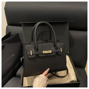 Dettaglio della borsa in pelle nera con finiture dorate e confezione regalo di lusso