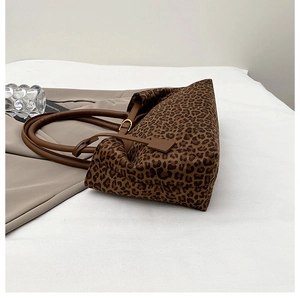 Detail of leopard print tote bag with brown leather handles and golden metal buckle