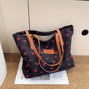 Large capacity black tote bag with cherry print and brown leather straps on white background